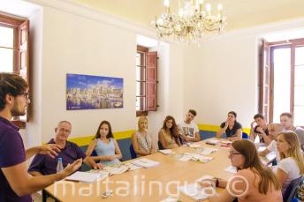 Mokytojas kalba klasėje, kurioje sėdi anglų kalbos studentai