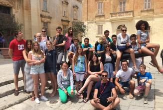 Mdinoje ant kanono sėdintys studentai